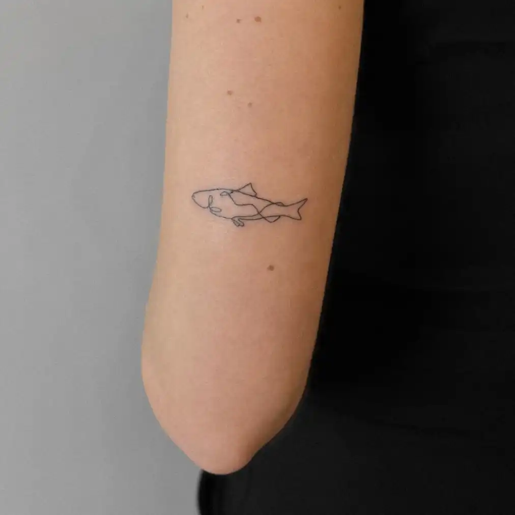 Tatuaje minimalista de un pez de línea fina en el brazo
