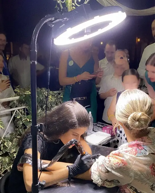 Tatuaje en directo durante una boda con invitados alrededor